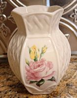 Front view of the Belleek vase showing the detailed basket weave pattern and the floral painting of a pink rose and two yellow buds.