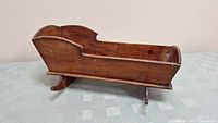 Full view of antique wooden toy cradle showing side profile and rocking legs.