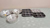 Photo of all bakeware items on a table including three springform pans and four muffin/tart pans