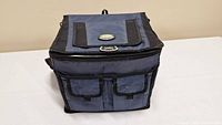 Blue insulated cooler bag showing front main compartment zipper and two small front pockets