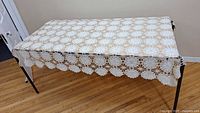 Full view of rectangular hand crocheted tablecloth draped over table, showing overall size and pattern.