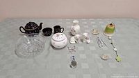 Overview of entire lot including ceramic teapot set, glass bowl, cat figurines, vases, and hanging decorations
