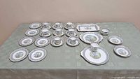 Full set of Royal Albert English bone china dessert ware, including plates, cups, saucers and serving tray, arranged on a green tablecloth.