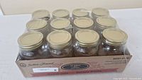 Twelve 500ml glass mason jars with metal lids, in original packaging.
