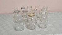Twelve clear glass mason jars with metal lids arranged on a table, showing their size and shape.