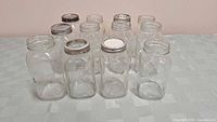 Ten one litre clear glass Mason jars, rectangular with embossed 'MASON' lettering, various metal lids, some rusted.