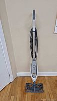 Full view of Shark floor steamer upright, showing white handle, main unit, and steam nozzle head on hardwood floor.