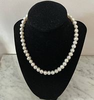 Front view of the vintage fresh water pearl necklace displayed on black bust showing length and pearl shape.