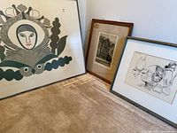 Overview of three framed art pieces leaning against wall