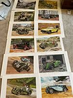 Photo showing 12 automobile art prints laid out on carpet, each depicting different vintage cars in scenic backgrounds.