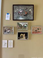 Photo showing all five framed illustrations mounted on wall: one large image at top center and four smaller images arranged below.