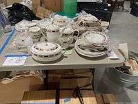 Full view of the Marlborough pattern china set spread out on a table, showing various stacked plates, bowls, pots, cups stacked with protective plastic wrapping in some pieces.