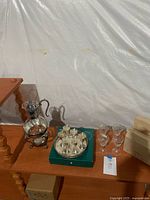 Photo showing glass coffee decanter on metal warming stand with candle, metal plate aperitif glasses on tray in original box, and four etched glass aperitif glasses on wooden table