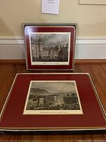Two placemats displayed, one depicting Edinburgh buildings, both framed with maroon and cream borders.