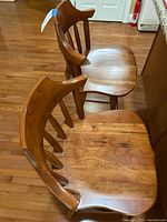 Two wooden Hunt Country bar stools side-by-side showing the seats and backs, wood grain visible.