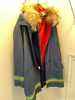 Blue Inuit parka hanging open, showing fur-lined hood and patterned trim on cuffs and hem
