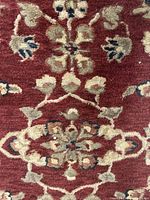 Close-up of detailed floral pattern on red background showing beige, navy, and olive accents