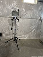 Full view of Kobalt flood light on black tripod stand in a basement-like space.