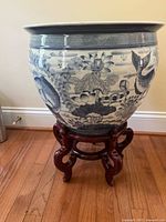 Full side view of the blue and white porcelain vase on the wooden stand showing fish and lotus decoration.