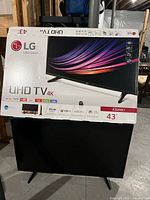 TV in original LG box showing UHD 4K branding, model 43UH61, and logos of streaming apps.