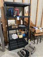 View of shelving unit loaded with various items, disassembled shelving at bottom, boxes and hardware items on shelves