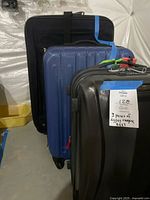Three suitcases: one large black soft-sided Globe Trotter expandable, one medium blue hard-shell Samsonite expandable, and one smaller black hard-shell Samsonite.
