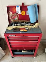 Front view of red Stack-On tool cart with open top lid showing various tools and accessories inside.