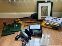 Overall view of all items in the lot including candlesticks, books, Garmin device, shaver, and tools