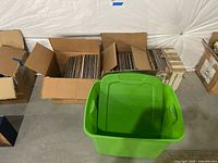 Three boxes of vintage record albums, mostly 33 RPM and some 78 RPM, arranged on floor with green plastic storage bin in front