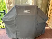 Covered Weber grill under fitted black cover on deck