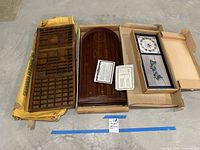 Wooden type set box, wooden marble game, and boxed Royal Air Force clock, all arranged side by side on a concrete floor.