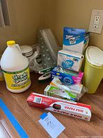 Lot overall showing cleaning supplies including Simple Green cleaner gallon jug, Ziploc Space Bags box, Stone Care Natural Cleaner box, Ziploc Snack Bags box, boxed iodized salt, wax paper roll and a yellow container with assorted storage bags.