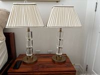 Pair of glass and brass table lamps on wooden surface, showing overall design and shades
