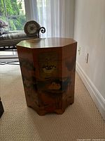 Front view of octagonal wooden hat box table showing hand-painted floral design and metal latch