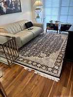 Full view of rectangular Persian rug under sofa showing overall pattern and fringe.