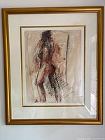 Framed watercolour painting showing a nude female figure from behind, hung on a white wall. The artwork is signed and framed with a gold frame and white matting with gold trim.