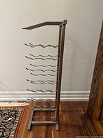 Front view of metal wine rack showing 6 curved bottle holders and vertical support frame.