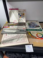 Photo showing rolling ruler boxes, multiple drawing pads including tracing pad, marker layout pad, and color theory wheel.