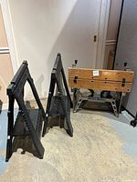 Black & Decker branded metal base work table with wooden top, alongside two black plastic collapsible saw horses