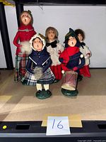 Five Byers' Choice Christmas Carolers figurines arranged on shelf showing all figures and attire