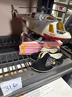 Photo of black 1960s Honor Guard children's shoes atop seven Playmore My Tiny 3-D Books with Tonka Rescue Helicopter on top