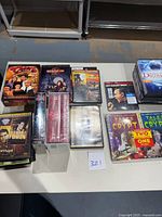 Photo showing various DVD sets and individual movie DVDs arranged on a table, including box sets of Tales From the Crypt, I Love Lucy, 24, Cheers, and Rescue Me, some still sealed in plastic.