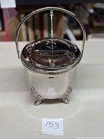 Front view of the pewter footed ice bucket with hinged lid and handle.