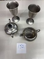 Set of 4 pewter items on white surface: two goblet-style cups, creamer, and sugar bowl with lid