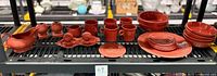 Complete 24-piece Fiestaware dining set in persimmon orange arranged on shelving