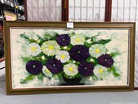 Full view of the framed floral painting showing purple and white flowers with a textured green background and artist's signature.
