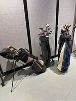 Three golf bags with assorted golf clubs each, showing full sets and overall condition