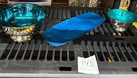 Three silver plated pieces: Two bowls and one oblong dish, blue and green tones, reflective surfaces, placed on black background