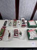 Seven Hallmark Keepsake Basketball Collector's Series glass ornaments in original boxes displayed together with some packed in bubble wrap. Two green large boxes included, one damaged.