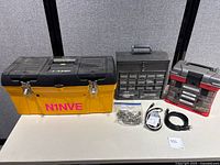 Wide shot of the lot showing a large yellow toolbox, two small parts organizer toolboxes, bag of connectors, and several cables and adapters on a table.